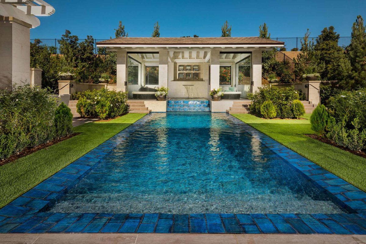 photo of a backyard pool design in PebbleTec Tropical Breeze Pool Finish medium blue water color with a waterfall feature