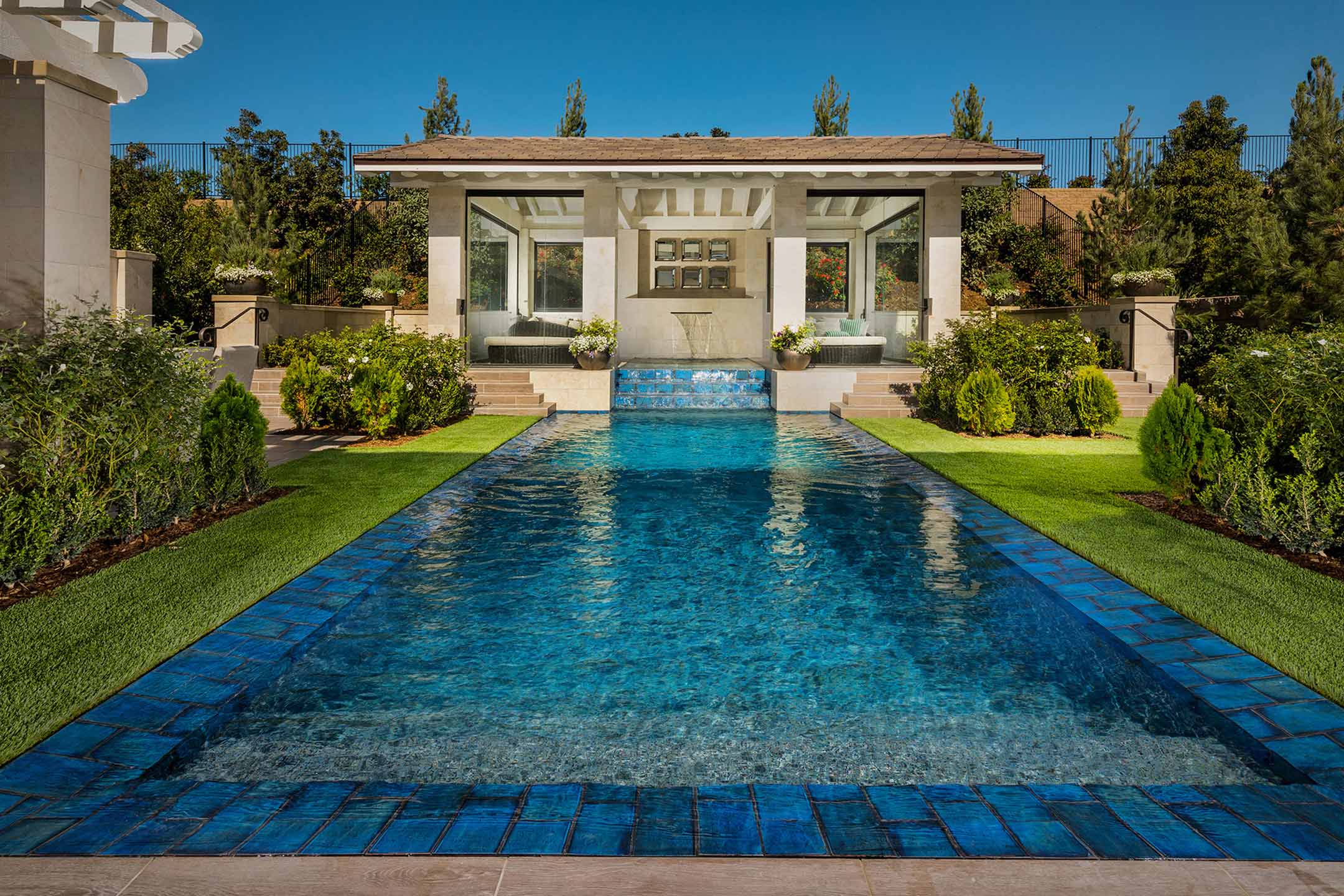 photo of a backyard pool design in PebbleTec Tropical Breeze Pool Finish medium blue water color with a waterfall feature