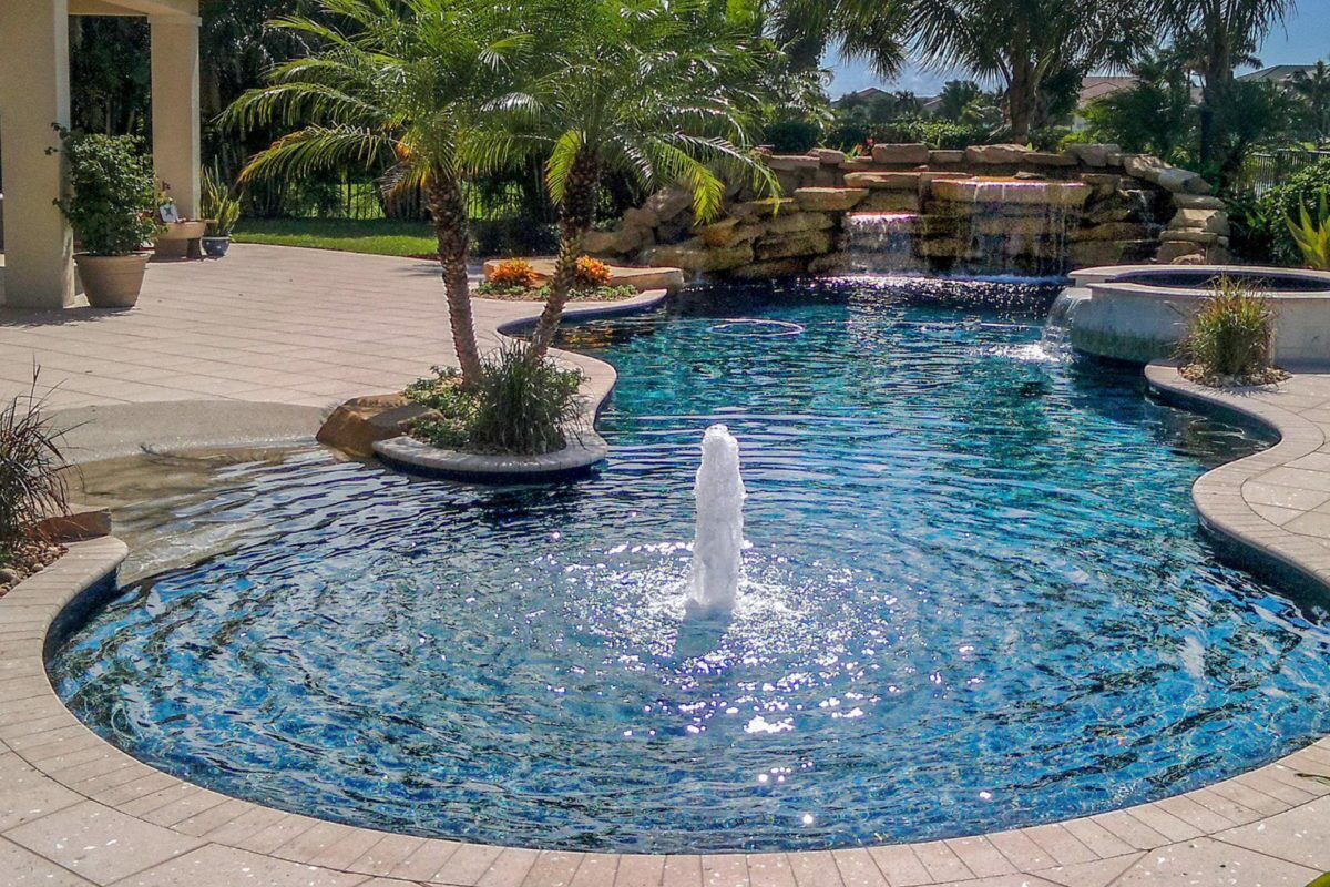 photo of a backyard pool design in PebbleTec PebbleBrilliance Deep Cove Pool Finish medium blue water color with a rock waterfall feature submitted for World's Greatest Pools 2017