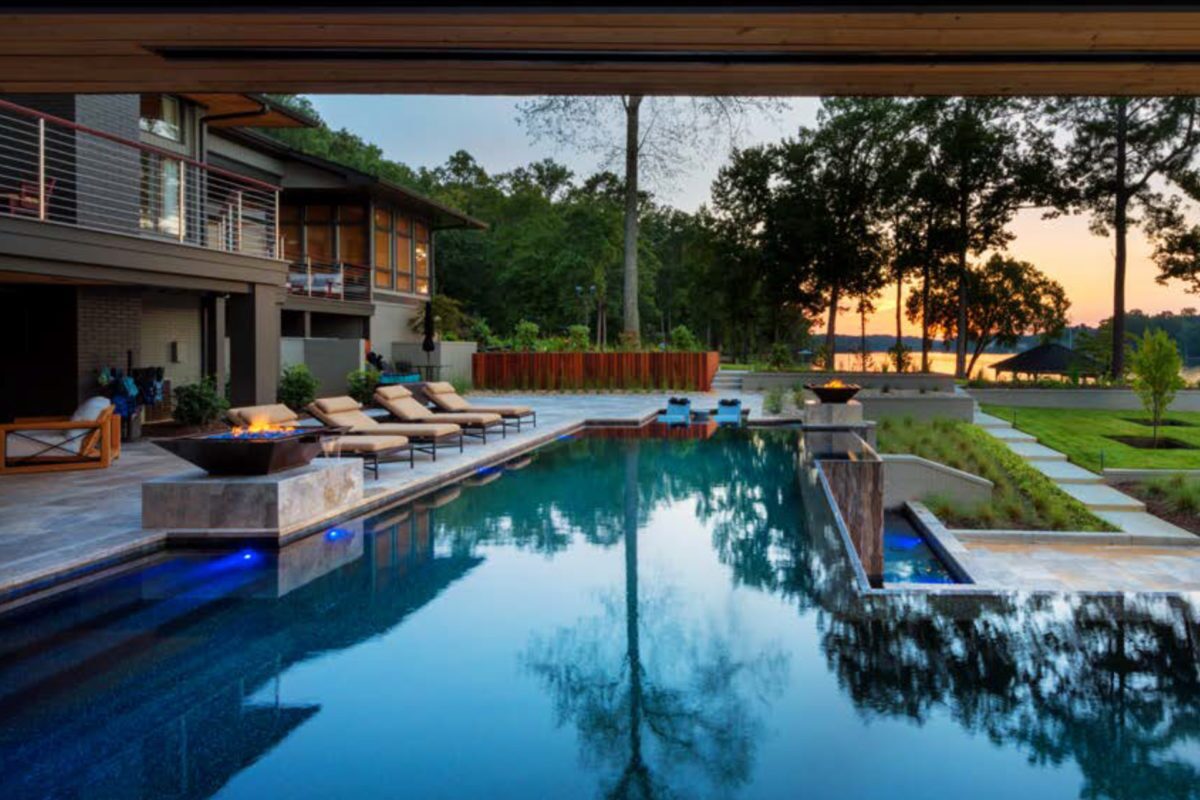 photo of a backyard pool design in PebbleTec Black Pearl Pool Finish dark blue water color at sunset with fire bowl features