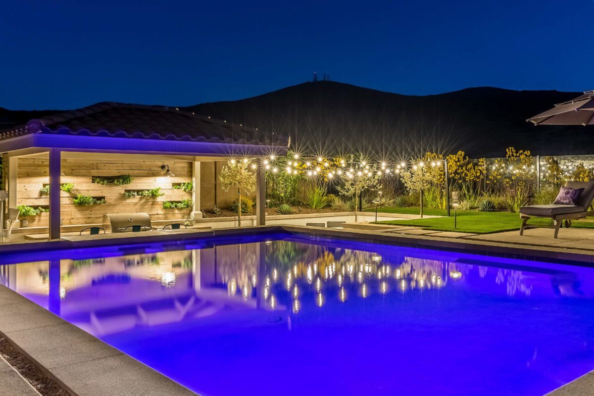 photo of a lit up pool in PebbleTec Tahoe Blue Pool Finish medium blue water color lit up in the evening