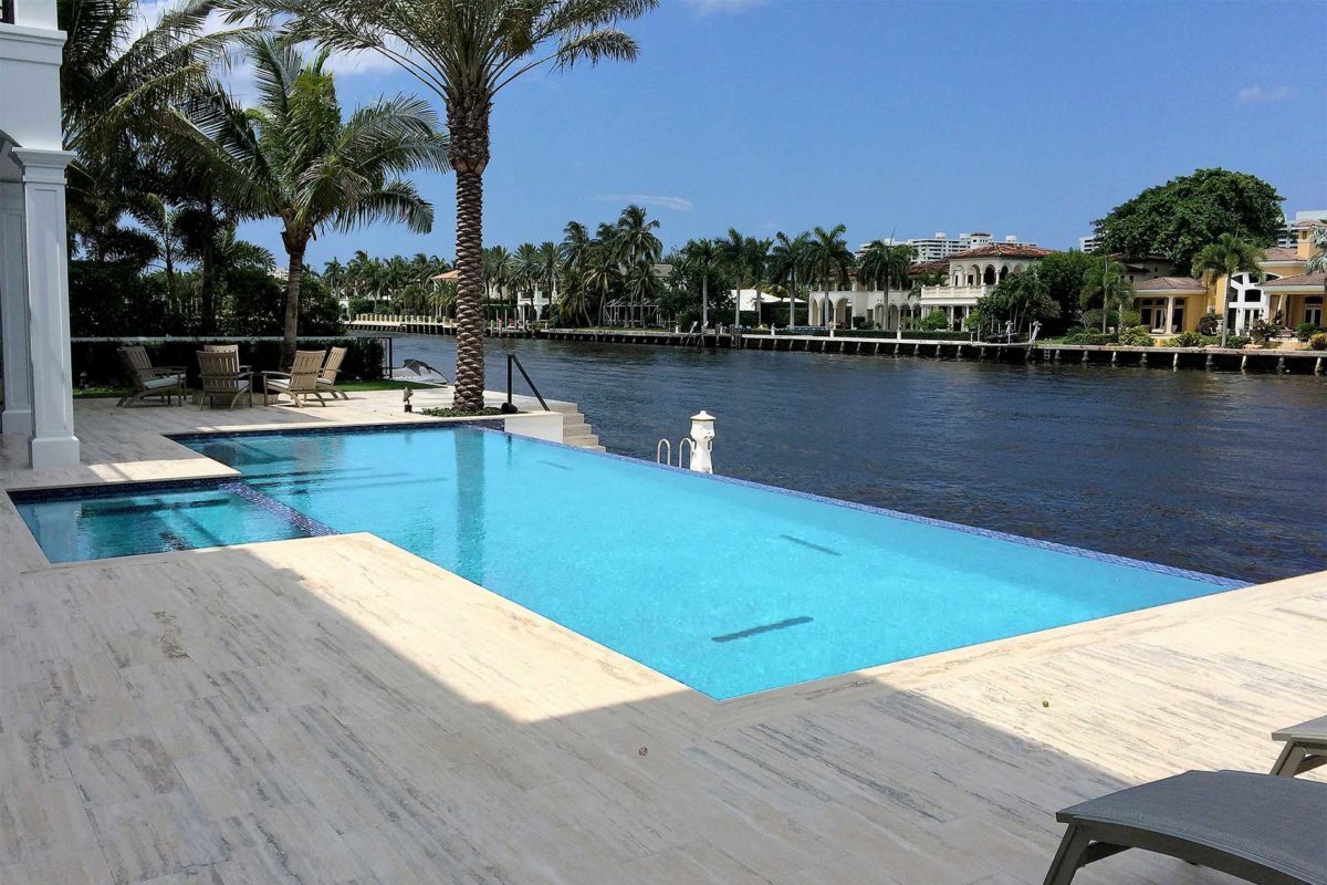 photo of a backyard pool and jacuzzi design on a river with a waterfall overhang in PebbleBreeze Gulf Shores Pool Finish by Star Light Pool Builders 2016 World's Greatest Pools