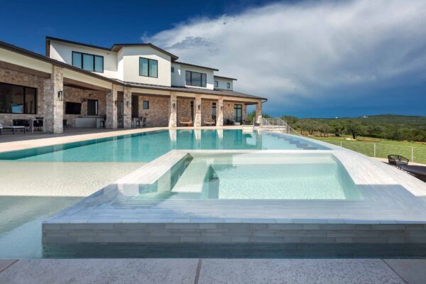 photo of light blue pool and spa in modern backyard
