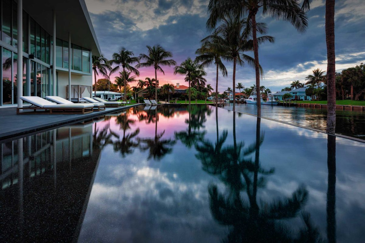 photo of a backyard pool design in PebbleTec Black Pearl Pool Finish dark blue water color at sunset on a canal