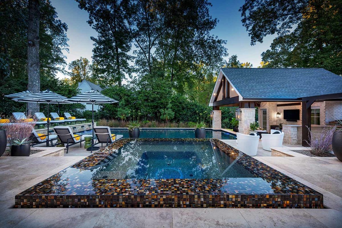 photo of a backyard pool and jacuzzi design in PebbleTec Black Marble Pool Finish: A rich blend of white pebbles and a subtle metallic luster produce a deep dark blue water color.