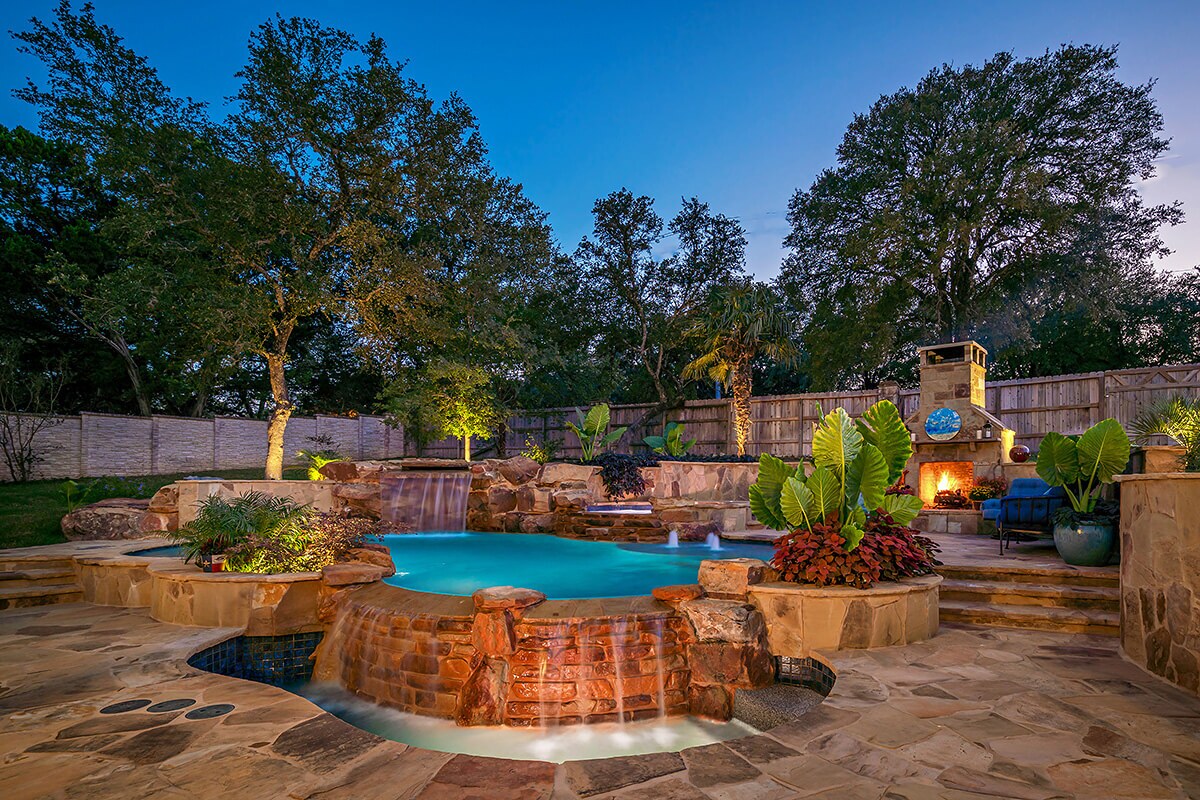 photo of a resort style backyard pool design in PebbleTec Tropical Breeze Pool Finish medium blue water color with waterfall features
