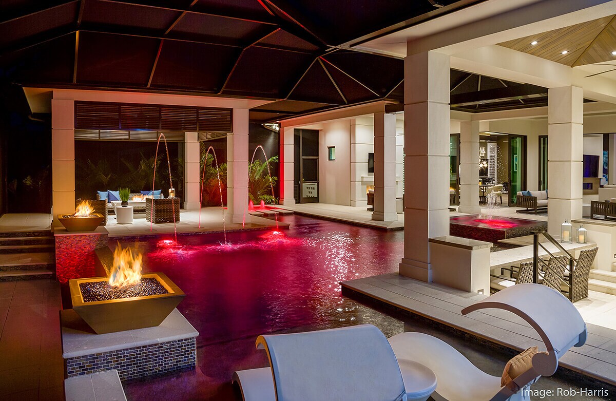 photo of a backyard design at night in PebbleTec Caribbean Blue Pool Finish with a red light feature