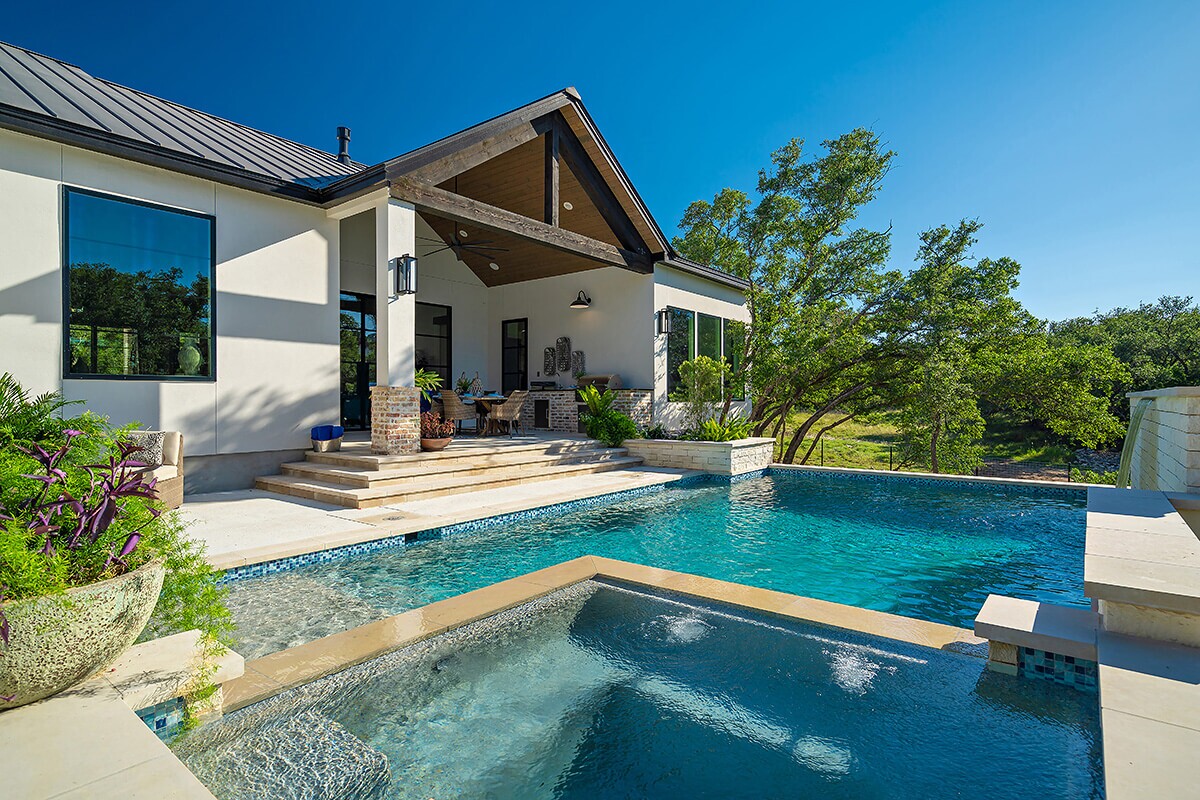 photo of a backyard waterfall pool design in PebbleTec Caribbean Blue Pool Finish medium blue water color with lightstreams tile features