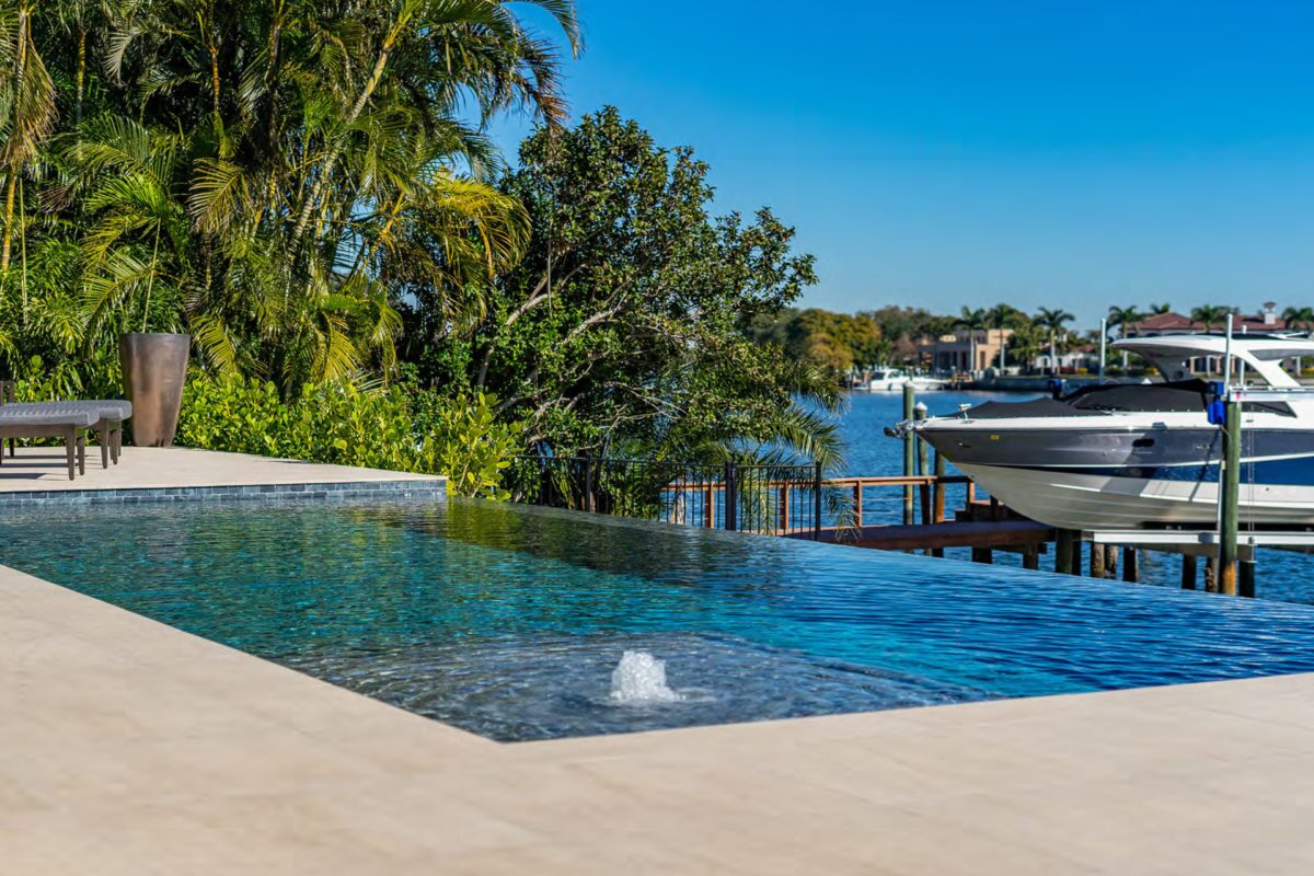 photo of a backyard waterfall pool design in PebbleTec PebbleBrilliance Majestic Sound Pool Finish medium blue water color with lightstreams tile features World's Greatest Pools 2021