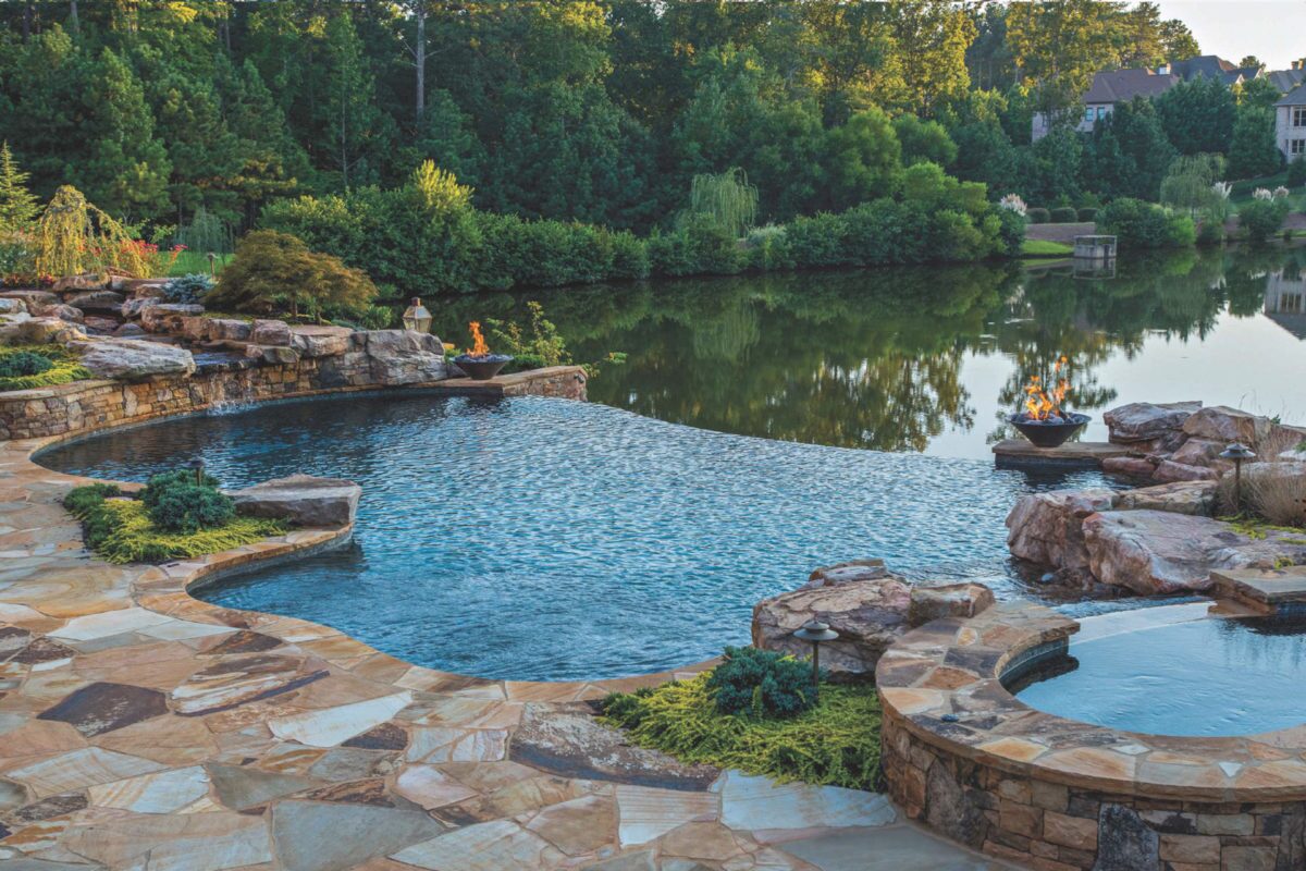 photo of a waterfall edge pool in PebbleTec Black Marble Pool Finish medium blue water color with fire bowl features with a lakeside view