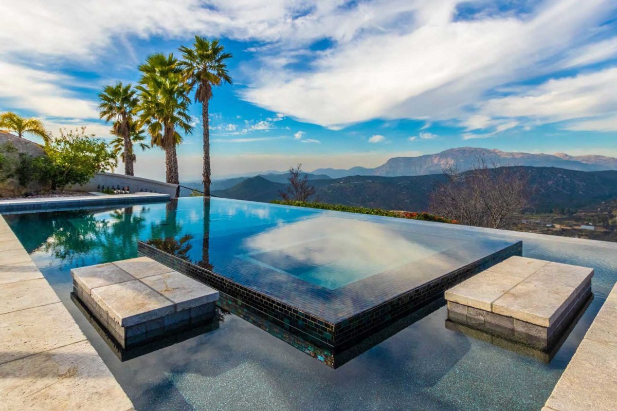 photo of a waterfall edge pool in PebbleTec Midnight Blue Pool Finish medium blue water color with a jacuzzi and Mountain View