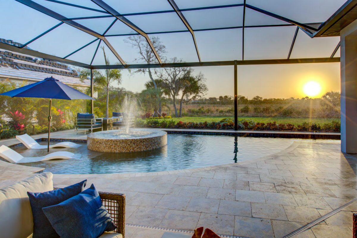 photo of an indoor pool at sunset in PebbleTec Sandy Beach Pool Finish medium blue water color with light streams tile and water feature for World's Greatest Pools 2019