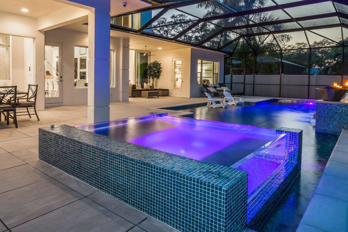 photo of an enclosed indoor backyard pool in the evening in PebbleTec White Pearl Pool Finish light blue water color with lightstreams tile and light features for World's Greatest Pools 2017