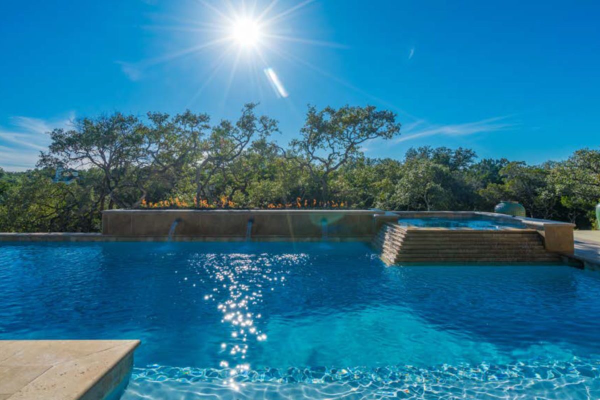 photo of pool in the daytime in PebbleTec White Pearl Pool Finish, light blue water color with waterfall water features for World's Greatest Pools 2018