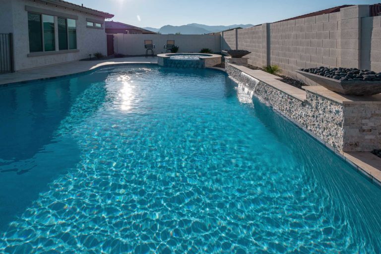 photo of backyard pool with water feature and fire bowl in PebbleBreeze Silver Sea water color pool finish at Casillas home