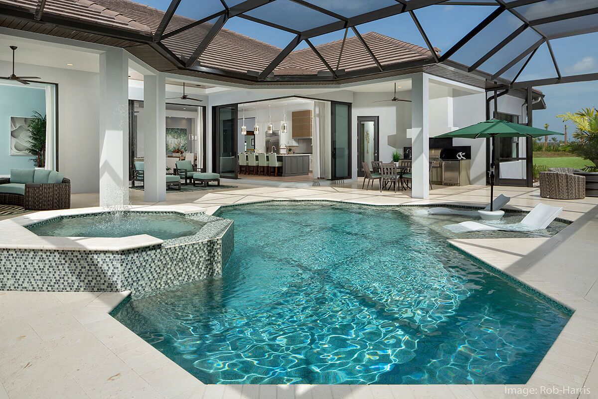 photo of a backyard waterfall pool design in PebbleTec Caribbean Blue Pool Finish medium blue water color with lightstreams tile features